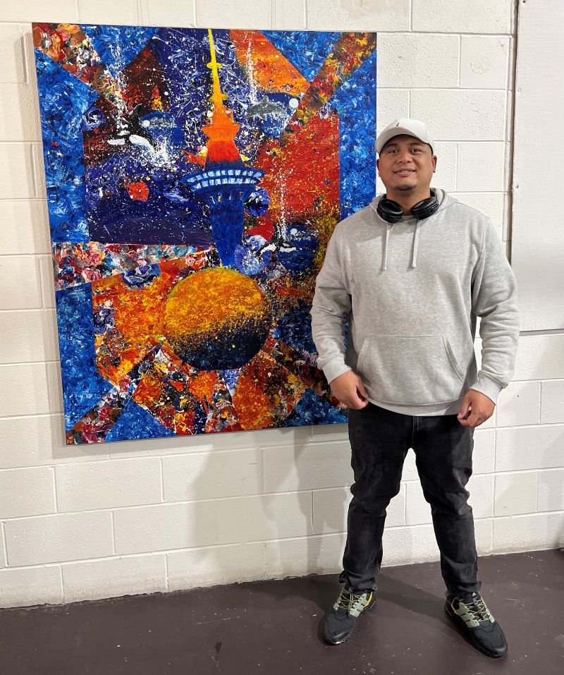 Toi Ora artist Rob Lehu-Moetara standing in front of his painting Portal