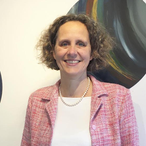 Susanne standing in a pink jacket with circular paintings behind her.