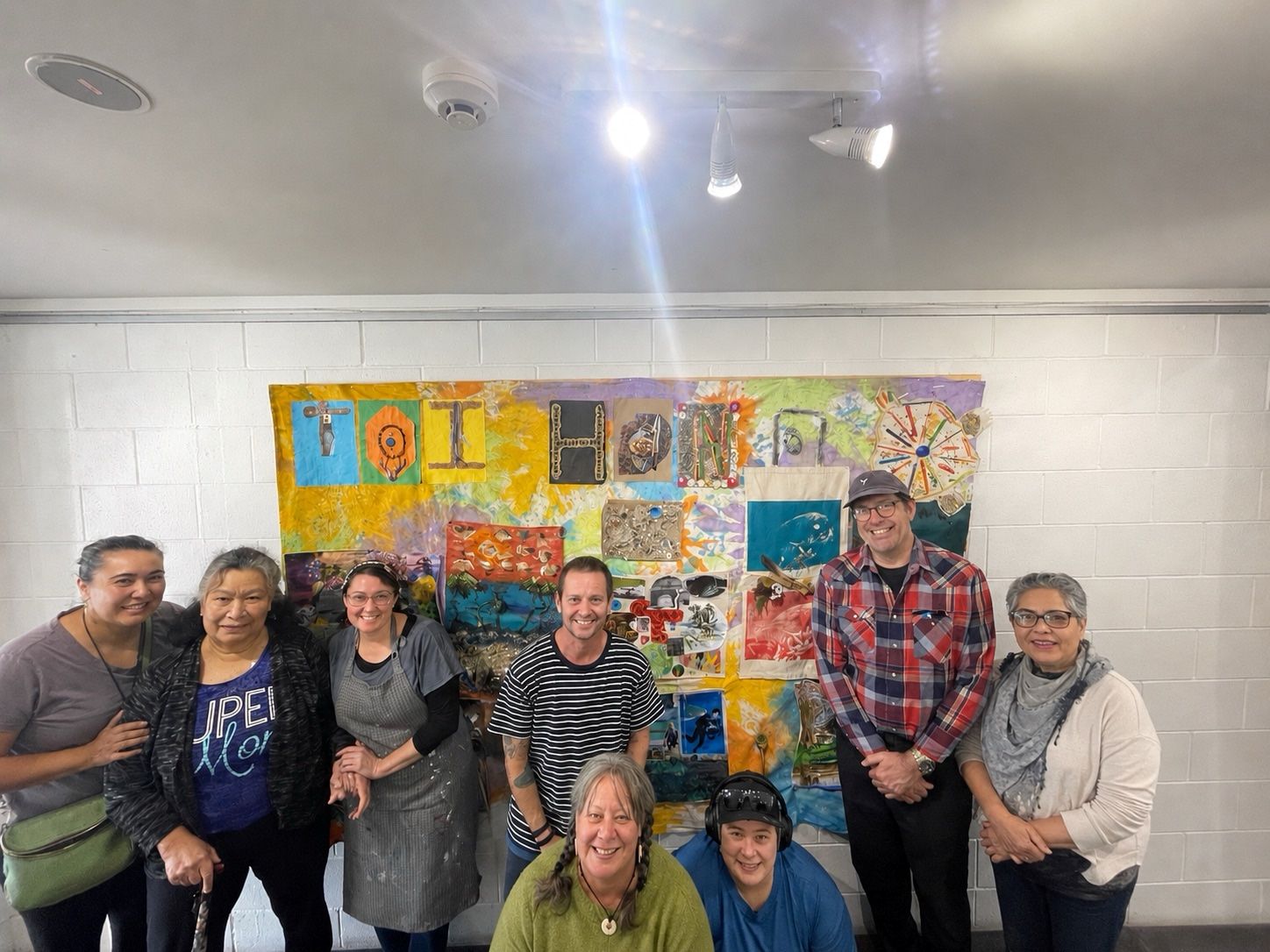 Artists from the Toi Hono art class gathered around their collaborative artwork